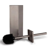 De Velasco Gunmetal toiletborstel van yessential.nl, met een vierkant handvat en zwarte borstelharen, staat voor zijn bijpassende vierkante houder. Deze vrijstaande roestvrijstalen set biedt een strakke, moderne look voor georganiseerde badkamers.