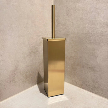 Een Velasco Gold toiletborstel van yessential.nl, vrijstaand met houder, staat in de hoek van een beige betegelde badkamer.
