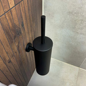 De Donato Black WC Set van yessential.nl is aan de muur bevestigd op een houten badkamermuur met beige en grijze tegels en voegt een strak accent toe aan je badkameraccessoires.