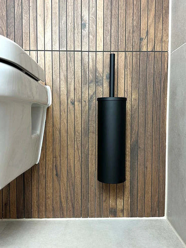 De Cosimo Black WC set van yessential.nl is gemonteerd op een houten wand naast een wit toilet in een moderne badkamer met grijze vloertegels en lichtbeige wandtegels - een elegante badkameraccessoires upgrade.