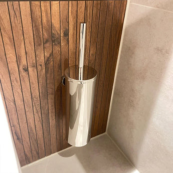 De Branco Chroom toiletborstelhouder van yessential.nl heeft een glanzend zilveren greep, aan de muur gemonteerd tegen verticale houten panelen naast lichtbeige betegelde muren en vloer.