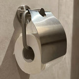 Een wc-rol is verkeerd geplaatst en hangt dicht tegen de muur onder een Julio RVS toiletrolhouder van yessential.nl in de badkamer.