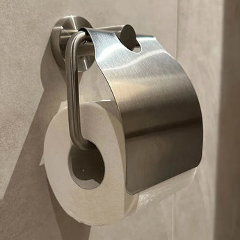 Een wc-rol is verkeerd geplaatst en hangt dicht tegen de muur onder een Julio RVS toiletrolhouder van yessential.nl in de badkamer.