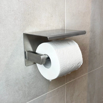 Toiletolhouder RVS gemonteerd op een beige betegelde badkamermuur, voegt moderne stijl toe aan je toilet met zijn strakke witte toiletpapierhouder.