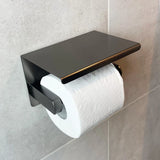 Een rol wit toiletpapier op de yessential.nl Tazio Gunmetal (No Drill) houder met een platte bovenkant, gemonteerd op een lichtgrijs betegelde badkamermuur.