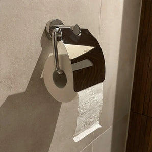 Een rol toiletpapier hangt aan de Julio Chrome toiletrolhouder met klep van yessential.nl, de glanzende deksel weerspiegelt de betegelde badkamer en versterkt de moderne look met stijlvolle toiletaccessoires.