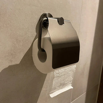 De Sandro Gunmetal WC-set van yessential.nl heeft een wc-papierrol op een wandhouder met metalen deksel, papier over de bovenkant en afrolbaar vanaf de wand - een ideale stijlvolle gunmetal toiletaccessoire voor de moderne badkamer.