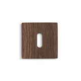 De Rosettes Walnut van yessential.nl is een vierkant, donkerbruin houten sleutelgatdeksel met een verticale ovale uitsparing, met zichtbare houtnerf en ideaal voor deurklink rozetten. Weergegeven op een witte achtergrond voor een opvallend contrast.