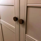 Close-up van twee Arriero Walnut knoppen van yessential.nl op crème paneeldeuren met geometrisch design, die de luxe uitstraling van deze design deurknoppen laten zien.