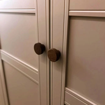 Close-up van twee Arriero Walnut knoppen van yessential.nl op crème paneeldeuren met geometrisch design, die de luxe uitstraling van deze design deurknoppen laten zien.