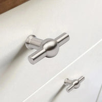 Close-up van een Rando RVS Knop van yessential.nl op een witte lade, met een andere identieke knop zichtbaar op de onderste lade in de achtergrond.
