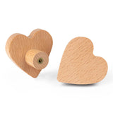 Twee Bambino Heart houten knoppen van yessential.nl worden getoond: een plat om de hartvorm te laten zien, de andere rechtop met de schroefbevestiging zichtbaar-perfect voor het toevoegen van een lief tintje aan de kinderkamer.