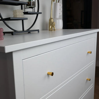 Een Kosmo dressoir met de yessential.nl Kosmo Gold Knob is vormgegeven met een ronde zwarte plank, roze en witte kaarsen en een gouden dierenbeeldje, allemaal tegen een witte muur.