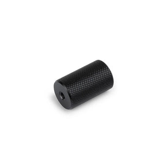 De Remo Black Deluxe knop van yessential.nl, een moderne cilindervormige greep met gekartelde textuur en centraal gat, wordt getoond tegen een witte achtergrond - ideaal als een stijlvolle hedendaagse kastknop.