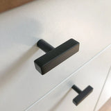 Close-up van twee Vasco Black Knobs van yessential.nl met een matte afwerking op een witte kast. Het moderne, eenvoudige ontwerp heeft strakke lijnen en een stijlvolle uitstraling.