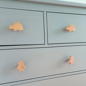 De Bambino Dino commode van yessential.nl is lichtgrijs en heeft vier speelse houten dierenknoppen - twee schildpadden bovenop en twee pinguïns onderaan - waardoor het de perfecte vrolijke aanvulling is op elke kinderkamer.
