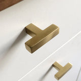 Close-up van twee Vigio Gold Knobs van yessential.nl op een witte kast, met zachte verlichting die het strakke, moderne matgouden ontwerp laat zien.