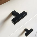 Close-up van een witte kast met moderne matzwarte Vigio Black knop van yessential.nl. Deze T-vormige handgrepen geven een stijlvol accent wanneer ze horizontaal op twee lades worden gemonteerd.