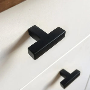 Close-up van een witte kast met moderne matzwarte Vigio Black knop van yessential.nl. Deze T-vormige handgrepen geven een stijlvol accent wanneer ze horizontaal op twee lades worden gemonteerd.