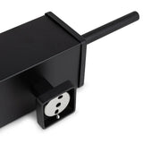 Een close-up van de Alessino Black stekkerdoos van yessential.nl, met een Europees stopcontact en zwart snoer, geplaatst naast een matzwarte toiletborstel voor een strakke, moderne badkamerstijl.