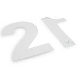 Twee grote, platte Adamo White huisnummers van 15 cm van yessential.nl liggen op een wit oppervlak. Elk huisnummer wit heeft kleine bevestigingsknijpers aan de achterkant - perfect om een stijlvolle touch toe te voegen aan de entree van je huis.