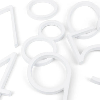 Verschillende grote, witte, plastic contouren - waaronder moderne huisnummers van yessential.nl - liggen verspreid op een wit oppervlak. De vormen creëren een abstract patroon geïnspireerd op het Amato White 20cm ontwerp.