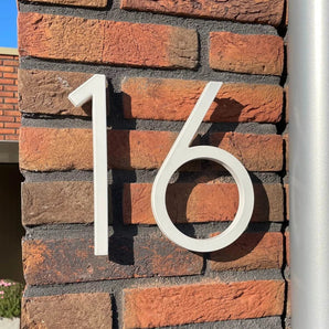 De Amato White 20cm van yessential.nl zijn moderne, witte huisnummers. Op een roodbruine bakstenen muur gemonteerd geven ze een stijlvol effect, waarbij het zonlicht een mooie schaduw op de stenen werpt. Een opvallend huisnummer!.